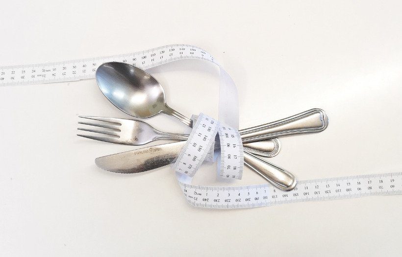 silver cutlery with a tape measure wrapped around them